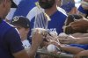 A Los Angeles Dodgers player, left, signs a miniature World Series trophy during a spring training baseball practice, Friday, Feb. 28, 2025, in Phoenix. (AP Photo/Darryl Webb)