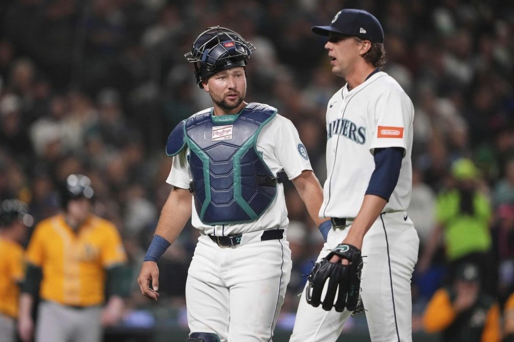 Seattle Mariners catcher Cal Raleigh, left, check on starting pitcher Logan Gilbert after Gilbert was hit by a line drive from Athletics' Lawrence Butler during the third inning of an opening-day baseball game, Thursday, March 27, 2025, in Seattle. (AP Photo/Lindsey Wasson)