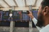 An investor takes a picture with a cell phone of indexes and benchmark 100 index at the Pakistan Stock Exchange (PSE), in Karachi, Pakistan, Monday, April 7, 2025. (AP Photo/Fareed Khan)