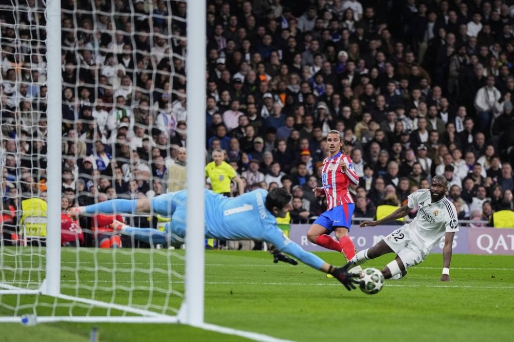 Real Madrid's goalkeeper Thibaut Courtois, left, makes a save in front Atletico Madrid's Antoine Griezmann, center, during the Champions League round of 16 first leg soccer match between Real Madrid and Atletico Madrid at the Bernebeu stadium in Madrid, Spain, Tuesday, March 4, 2025. (AP Photo/Manu Fernandez)