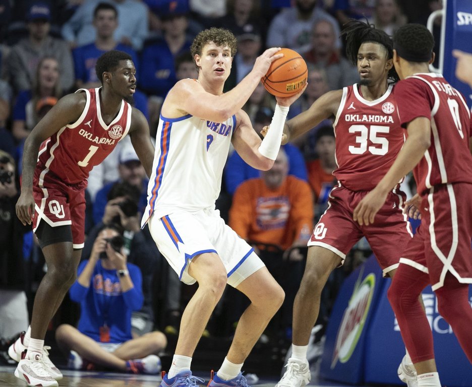 Florida center Micah Handlogten passes under pressure from Oklahoma forward Glenn Taylor Jr. (35) during the first half of an NCAA college basketball game, Tuesday, Feb. 18, 2025, in Gainesville, Fla. (AP Photo/Alan Youngblood)