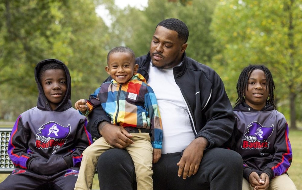 Shaquille Latimore, second from right, sits with two players on the youth football league he assistant coaches at a park in south St. Louis on Thursday, Oct. 19, 2023. (Allie Schallert/St. Louis Post-Dispatch via AP)