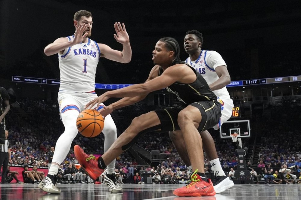 UCF's Keyshawn Hall (4) chases a loose ball as Kansas' Hunter Dickinson (1) and Flory Bidunga, right, defend during the first half of an NCAA college basketball game in the second round of the Big 12 Conference tournament, Wednesday, March 12, 2025, in Kansas City, Mo. (AP Photo/Charlie Riedel)