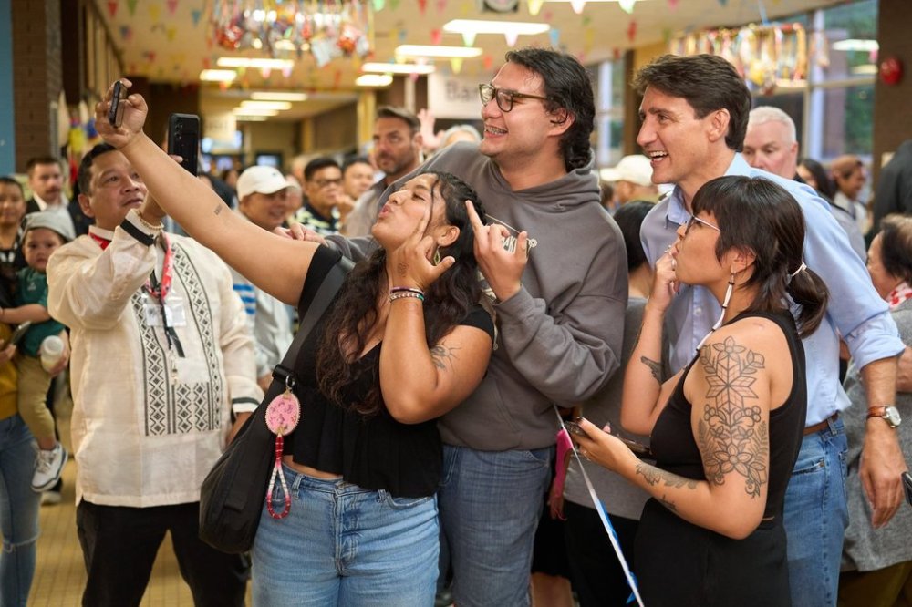 Prime Minister Justin Trudeau poses for a photo as people attending the event give him the middle finger gesture at the Folklorama Filipino Pavilion in Winnipeg, Monday, Aug. 5, 2024, at R.B. Russell Vocational School. THE CANADIAN PRESS/David Lipnowski