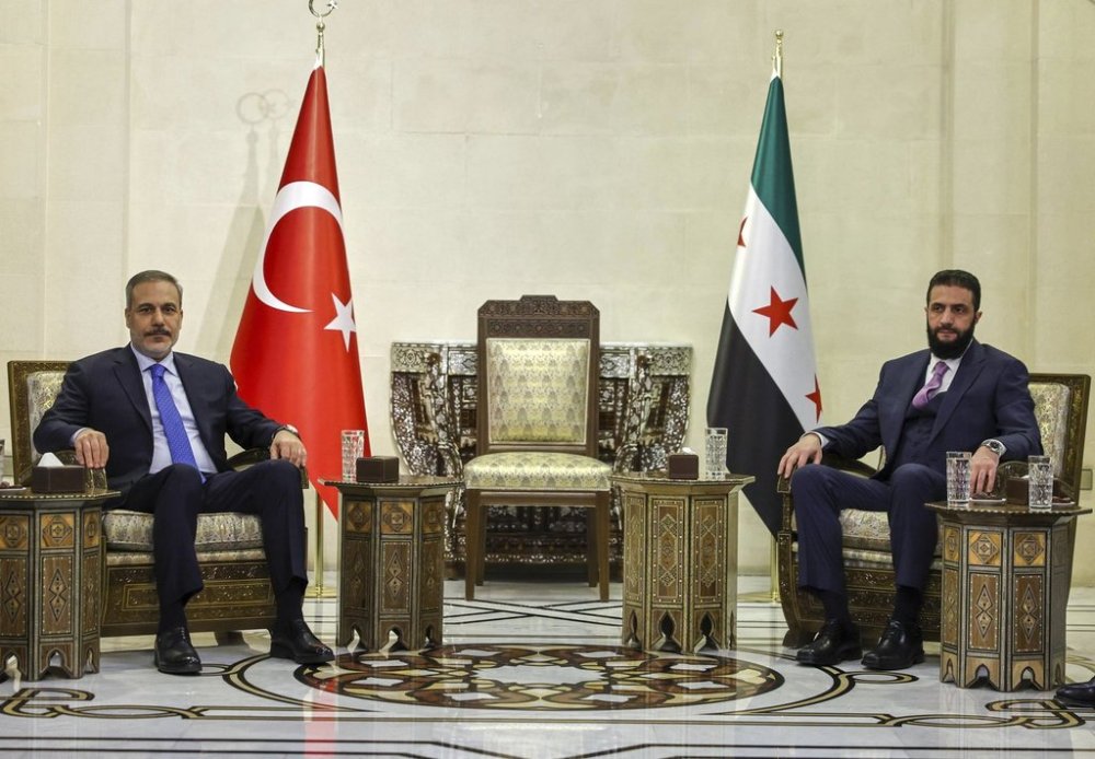 In this handout photo released by the Turkish Foreign Ministry press service, Turkish Foreign Minister Hakan Fidan, left, sits with Syria's interim president Ahmad Al-Sharaa, during their meeting in Damascus, Syria, Thursday, March 13, 2025. (Turkish Foreign Ministry press service via AP)