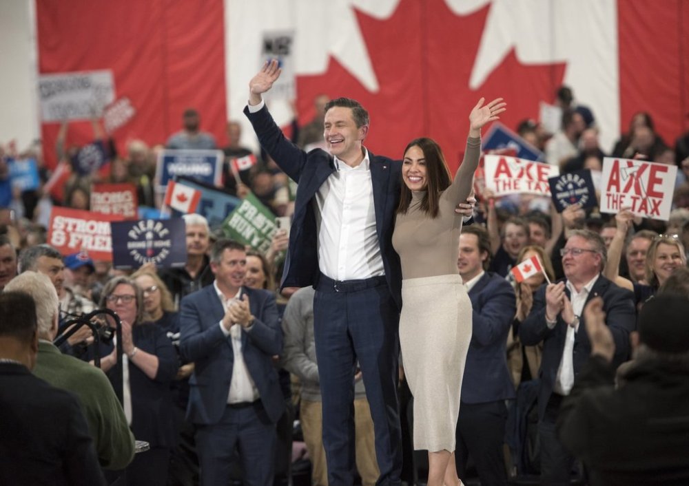 Conservative Leader Pierre Poilievre and his wife Anaida Poilievre look out at the crowd at a rally in Fredericton, N.B., on Monday, March 31, 2025. THE CANADIAN PRESS/Stephen MacGillivray