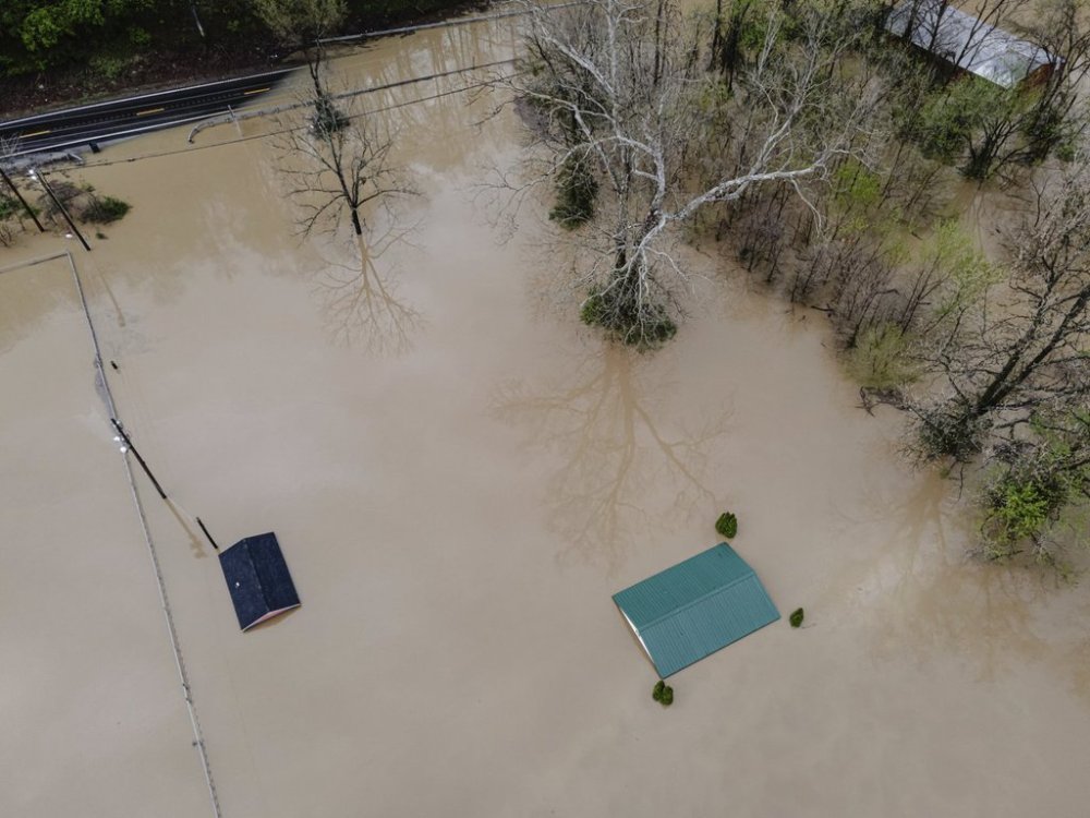 An aerial view of buildings and vehicles on a flooded property Saturday, April 5, 2025, in Frankfort, Ky. (AP Photo/Jon Cherry)