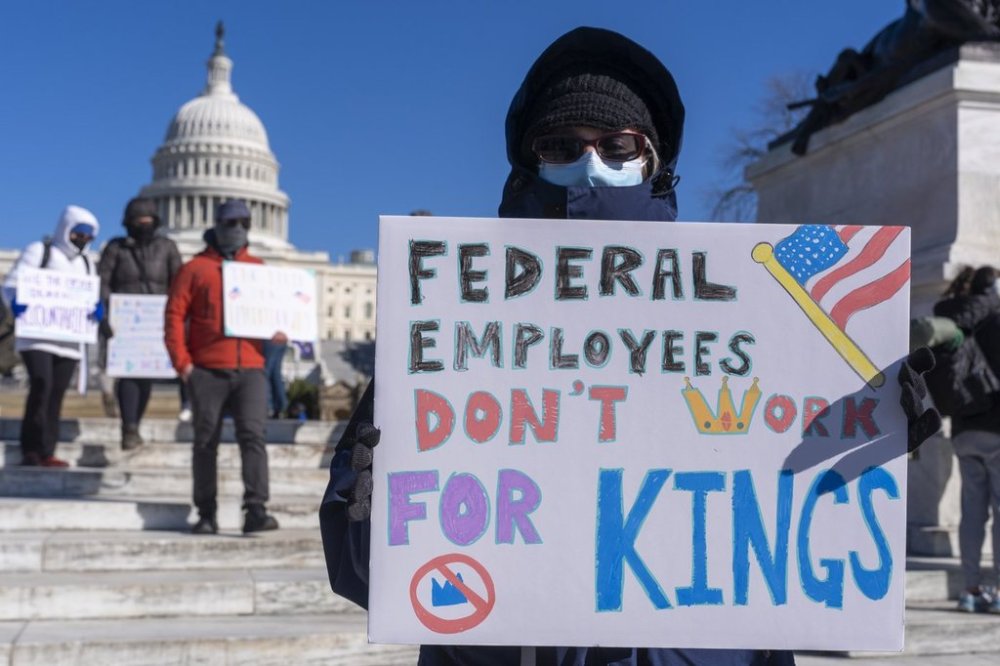 FILE - A federal employee, who asked not to use their name for fears over losing their job, protests with a sign saying