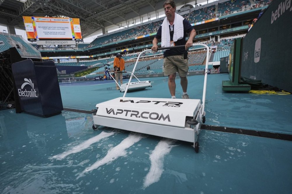 A crew dries the court after a break in rain that had delayed play by several hours, at the Miami Open tennis tournament, Sunday, March 30, 2025, in Miami Gardens, Fla. (AP Photo/Rebecca Blackwell)