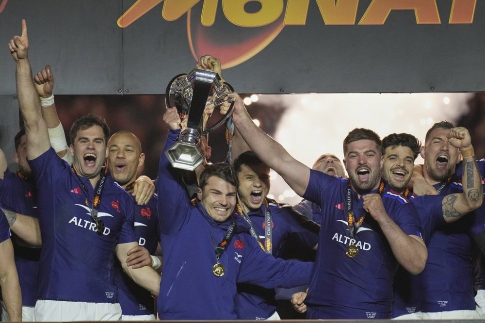The French team players Antoine Dupont, center, and Gregory Alldritt, right, celebrate with the trophy after the Six Nations rugby union match between France and Scotland at the Stade de France in Saint-Denis, outside Paris, Saturday, March 15, 2025. (AP Photo/Christophe Ena)