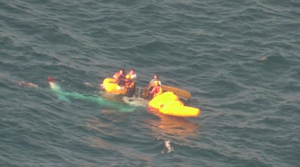 In this image released by the 7th Regional Japan Coast Guard Headquarters, rescuers work near people aboard a medical transport helicopter after it fell into the sea in southwestern Japan Sunday, April 6, 2025. (The 7th Regional Japan Coast Guard Headquarters via AP)