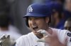 Los Angeles Dodgers' Shohei Ohtani, top, celebrates in the dugout after hitting a solo home run during the seventh inning of a home-opening baseball game against the Detroit Tigers, Thursday, March 27, 2025, in Los Angeles. (AP Photo/Mark J. Terrill)