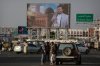 Yemenis stand under a street billboard displaying a picture of Abdul Malik al-Houthi, the leader of the Houthi movement, in Sanaa, Yemen, Tuesday, March 18, 2025. (AP Photo/Osamah Abdulrahman)