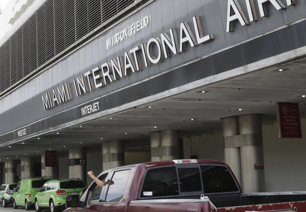 FILE - Vehicles drive past the entrance to Miami International Airport in Miami on Tuesday, May 12, 2020, (AP Photo/Wilfredo Lee, File)