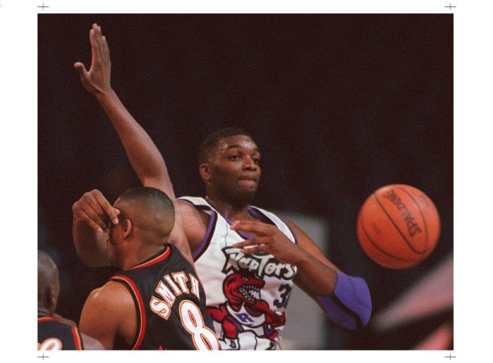 (CPT 115) TORONTO, Mar. 26 — Toronto Raptors centre Oliver Miller makes a pass around the head of an unsuspecting Atlanta Hawks guard Steve Smith during first quarter NBA action in Toronto Tuesday night.(CP PHOTO) 1996 (stf-Frank Gunn)fng
