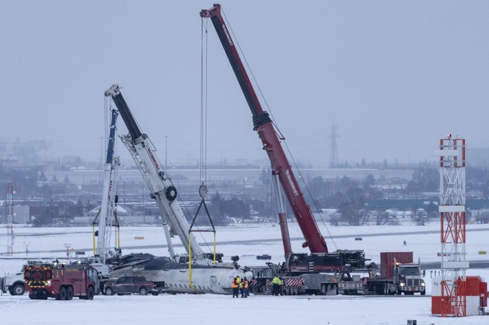 Cranes are positioned to remove the wreckage of Delta Flight 4819 from the runway at Toronto Pearson International Airport, in Mississauga, Ont., on Wednesday, February 19, 2025. THE CANADIAN PRESS/Arlyn McAdorey