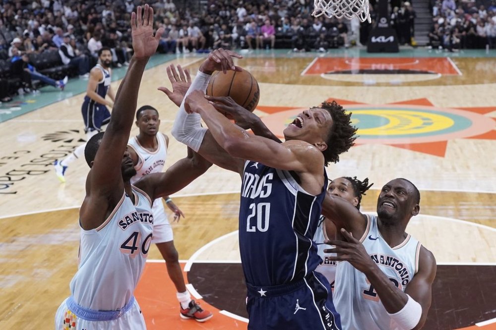 Dallas Mavericks forward Kessler Edwards (20) is blocked by San Antonio Spurs forward Harrison Barnes (40) as he drives to the basket during the first half of an NBA basketball game in San Antonio, Wednesday, March 12, 2025. (AP Photo/Eric Gay)