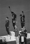 FILE -Extending gloved hands skyward in racial protest, U.S. athletes Tommie Smith, center, and John Carlos stare downward during the playing of the Star Spangled Banner after Smith received the gold and Carlos the bronze for the 200-meter run at the Summer Olympic Games in Mexico City on Oct. 16, 1968. Australian silver medalist Peter Norman is at left. Lord David Burghley who presented the medals is standing bottom center. (AP Photo, File)