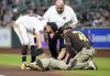 San Diego Padres' Luis Arraez lies on the ground after a collision with with Houston Astros second baseman Mauricio Dubon, left, as Padres first base coach David Macias (46) along with an Astros' trainer check on him at first base during the first inning of a baseball game Sunday, April 20, 2025, in Houston. (AP Photo/Karen Warren)