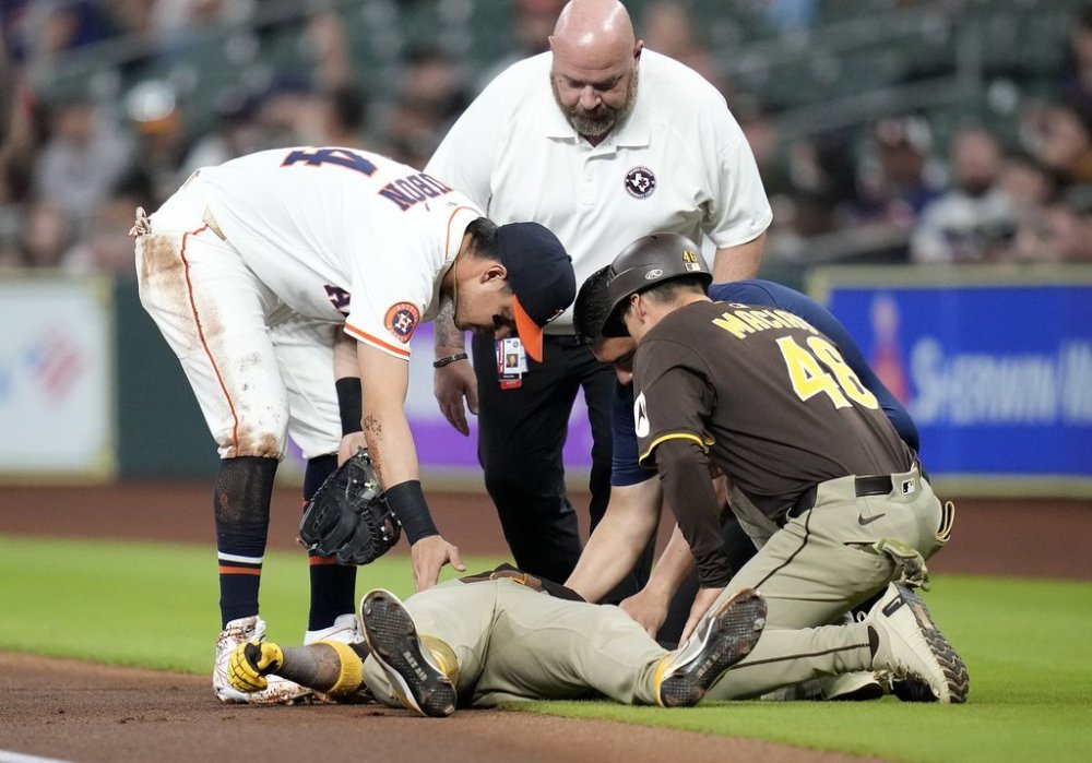 San Diego Padres' Luis Arraez lies on the ground after a collision with with Houston Astros second baseman Mauricio Dubon, left, as Padres first base coach David Macias (46) along with an Astros' trainer check on him at first base during the first inning of a baseball game Sunday, April 20, 2025, in Houston. (AP Photo/Karen Warren)