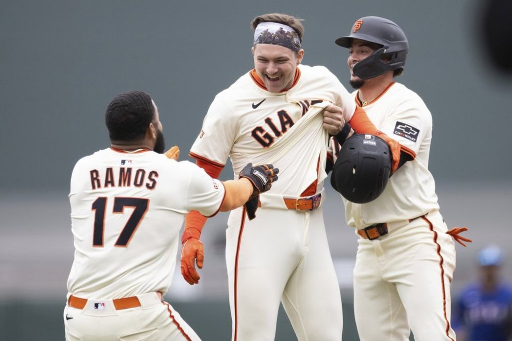San Francisco Giants catcher Patrick Bailey, center, is congratulated by Heliot Ramos (17), and Willy Adames after hitting a walk off single during the ninth inning of a baseball game against the Texas Rangers, Saturday, April 26, 2025, in San Francisco. (AP Photo/Benjamin Fanjoy)