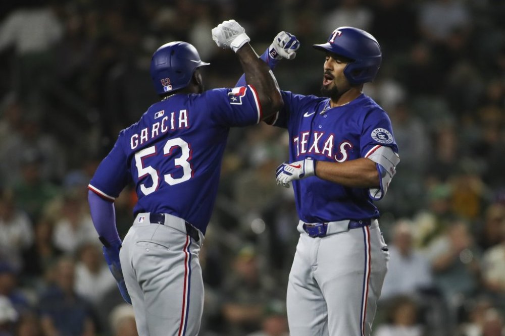 Texas Rangers' Marcus Semien, right, celebrates with teammate Adolis García (53) after hitting a three-run home run against the Athletics during the fifth inning of a baseball game Tuesday, April 22, 2025, in West Sacramento, Calif. (AP Photo/Scott Marshall)