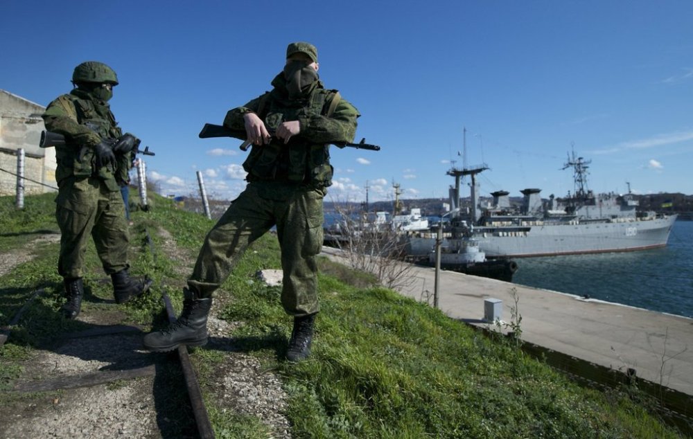 FILE - Russian soldiers guard a pier where two Ukrainian naval vessels are moored, in Sevastopol, on the Crimean Peninsula, March 5, 2014. (AP Photo, File)