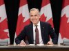 Prime Minister Mark Carney smiles as he takes his seat at his first news conference since winning the federal election, in Ottawa, Friday, May 2, 2025. THE CANADIAN PRESS/Adrian Wyld