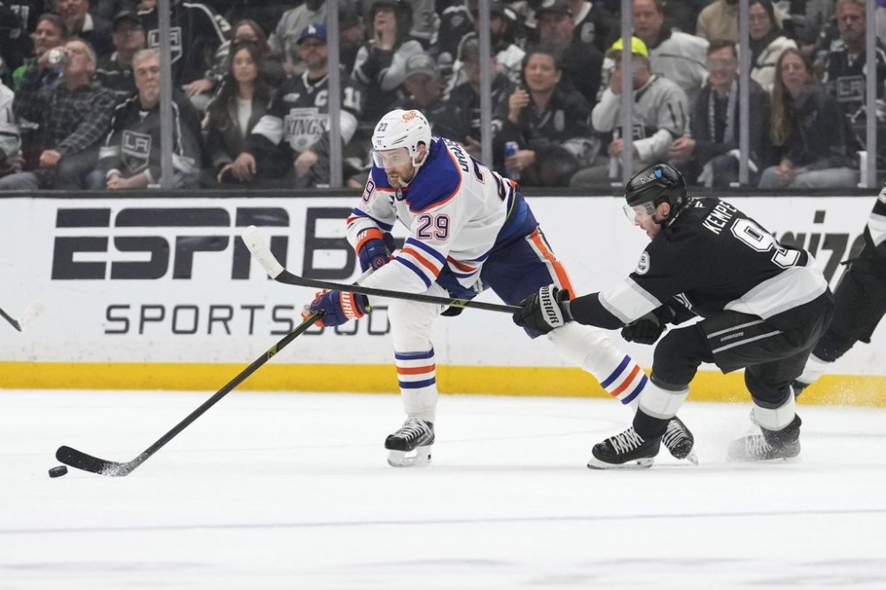 Edmonton Oilers centre Leon Draisaitl, left, passes the puck while under pressure from Los Angeles Kings right wing Adrian Kempe during the third period in Game 5 of an NHL hockey first-round playoff series Tuesday, April 29, 2025, in Los Angeles. (AP Photo/Mark J. Terrill)