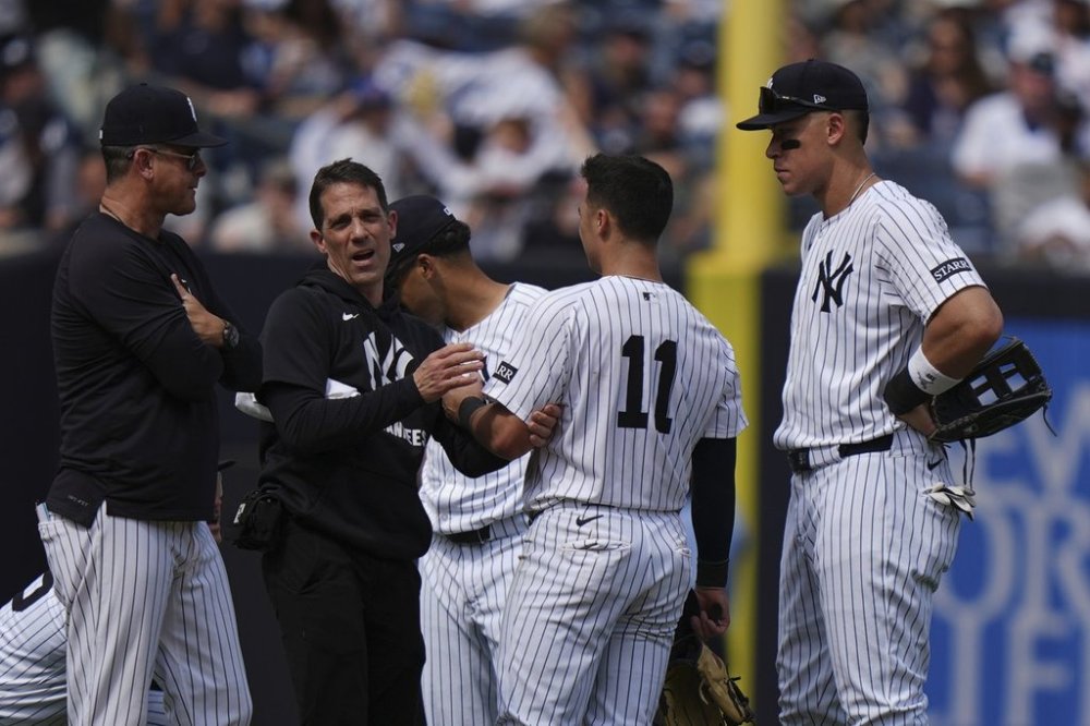 New York Yankees' Aaron Judge, right, and manager Aaron Boone, left, watch as a trainer checks on Anthony Volpe during the eighth inning of a baseball game against the Tampa Bay Rays Saturday, May 3, 2025, in New York. (AP Photo/Frank Franklin II)