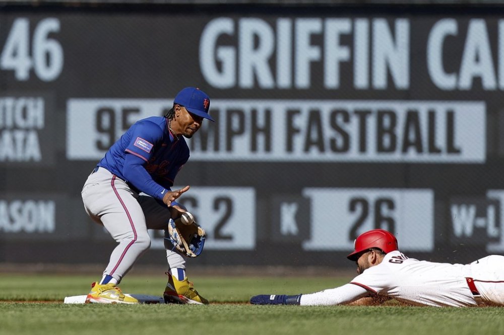 Washington Nationals' Luis García Jr., right, avoids a tag by New York Mets shortstop Francisco Lindor, left, and steals second base during the first inning of a baseball game in Washington, Monday, April 28, 2025. (AP Photo/Terrance Williams)