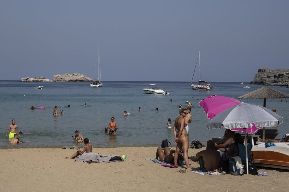 FILE - Tourists enjoy the beach and the sea in Lindos, on the Aegean Sea island of Rhodes, southeastern Greece, on Thursday, July 27, 2023. (AP Photo/Petros Giannakouris, File)