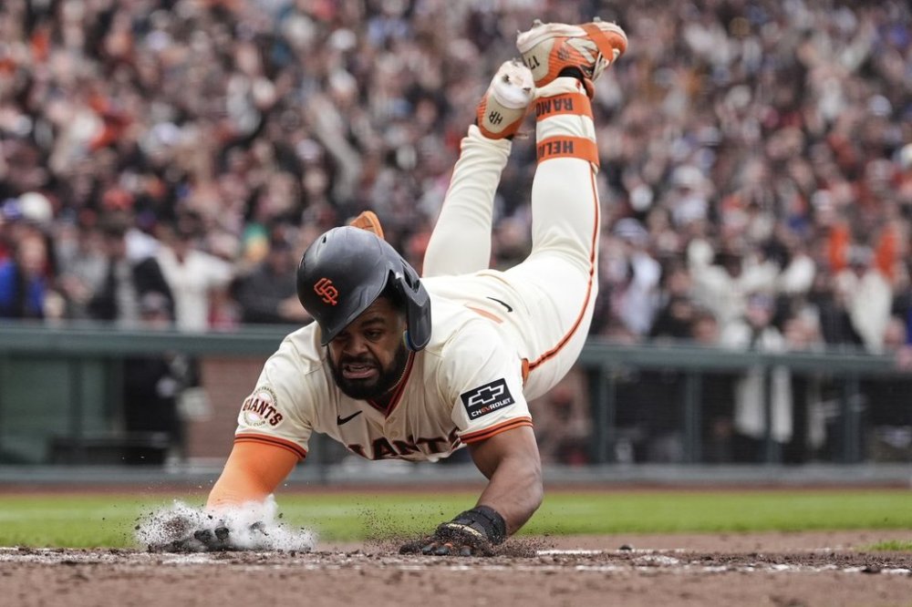 San Francisco Giants' Heliot Ramos scores the game-winning run on a throwing error Texas Rangers first baseman Jake Burger during the ninth inning of a baseball game Sunday, April 27, 2025, in San Francisco. (AP Photo/Godofredo A. Vásquez)