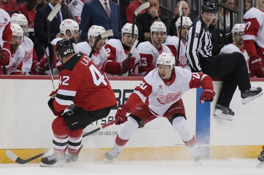 Detroit Red Wings' Albert Johansson, right, and New Jersey Devils' Curtis Lazar battle for the puck during the first period of an NHL hockey game in Newark, N.J., Wednesday, April 16, 2025. (AP Photo/Seth Wenig)