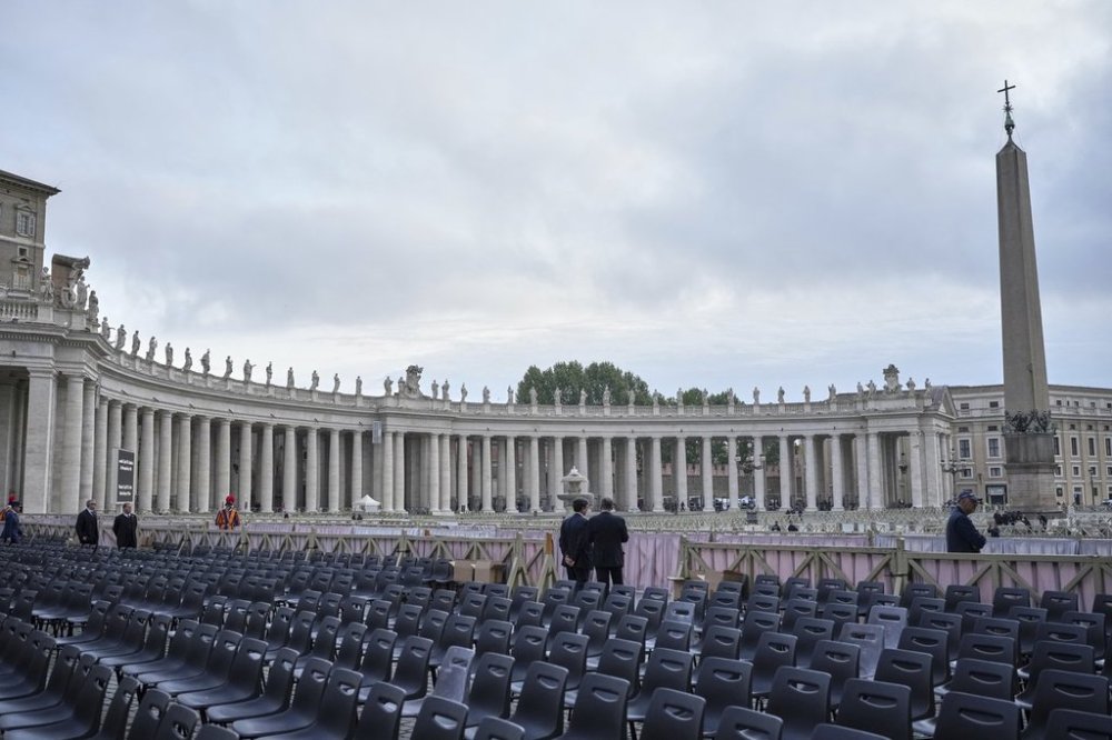 Two men stand near chairs during the preparations in St. Peter's Square ahead of the arrival of the body of Pope Francis, who will lie in state at St. Peter's Basilica for three days, at the Vatican, Wednesday, April 23, 2025. (AP Photo/Alessandra Tarantino)
