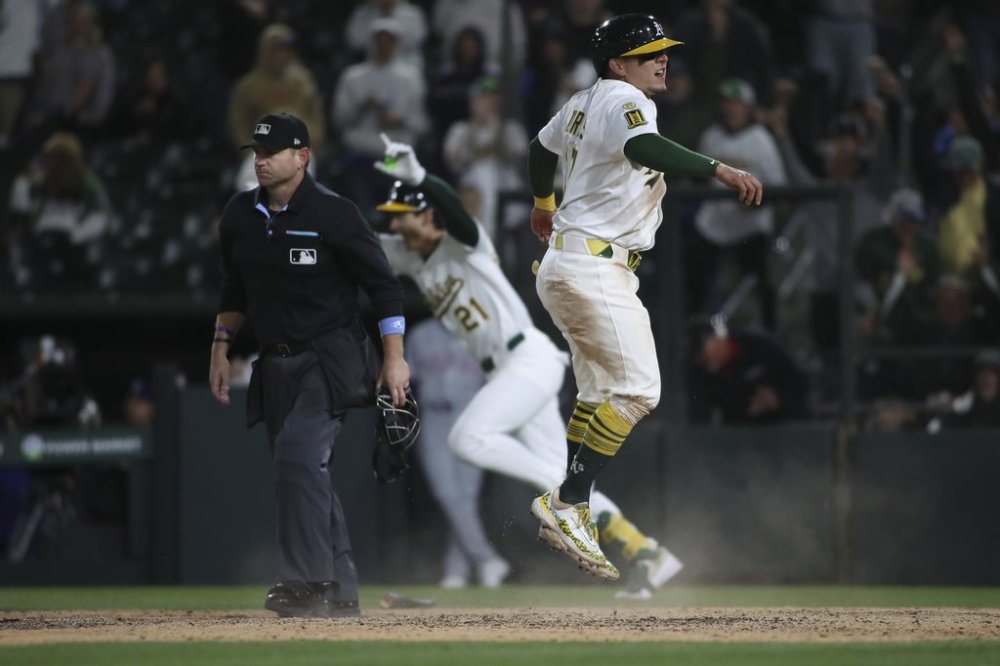 Athletics Luis Urías, right, slides into home safely to score the game winning run against the Texas Rangers during the ninth inning of a baseball game Thursday, April 24, 2025, in West Sacramento, Calif. (AP Photo/Scott Marshall)