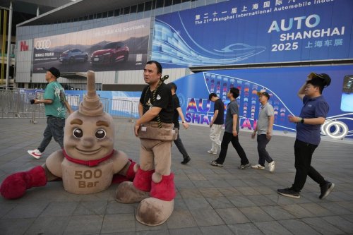 A worker takes a break from acting as a mascot outside the Shanghai auto show on Wednesday, April 23, 2025. (AP Photo/Ng Han Guan)