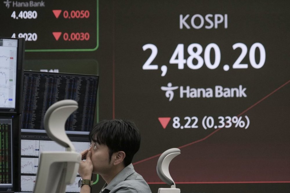 A currency trader watches monitors near a screen showing the Korea Composite Stock Price Index (KOSPI) at the foreign exchange dealing room of the KEB Hana Bank headquarters in Seoul, South Korea, Tuesday, April 22, 2025. (AP Photo/Ahn Young-joon)