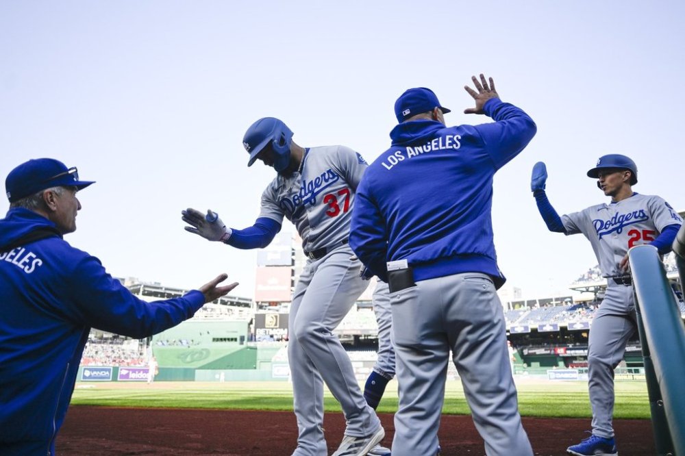 Los Angeles Dodgers Teoscar Hernández (37) is greeted at the dugout after he hit a two run home run driving in Dodgers Tommy Edman, right, during the first inning of a baseball game against the Washington Nationals Wednesday, April 9, 2025, in Washington. (AP Photo/John McDonnell)
