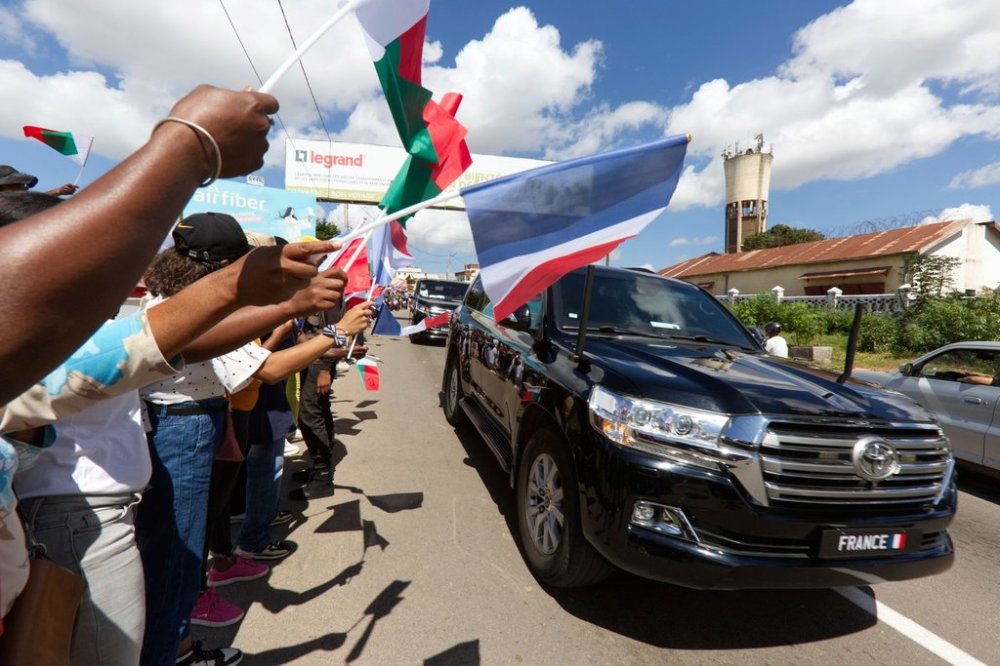 Residents wave flags at French President Emmanuel Macron upon his arrival in Antananarivo, Madagascar, Wednesday, April 23, 2025. (AP Photo/Alexander Joe)