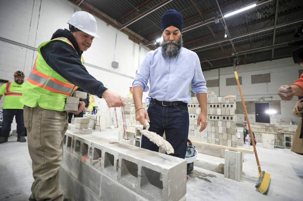 Federal NDP leader Jagmeet Singh learns to lay bricks with the help of student Greg Wood during tour of the training facility at Manitoba Building Trades Institute after Singh’s news conference Wednesday. (Ruth Bonneville / Free Press)
