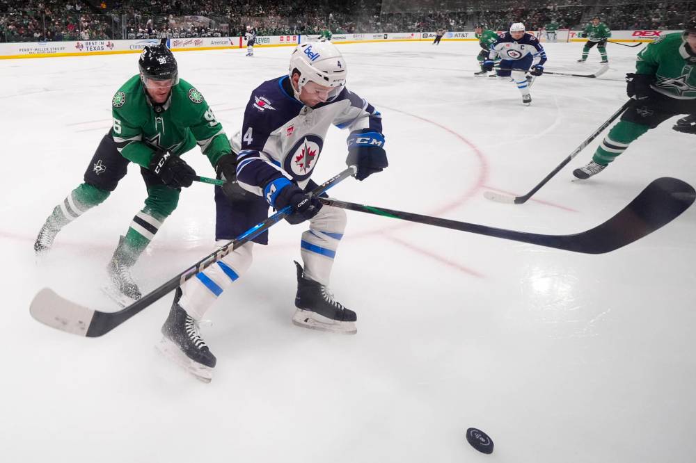 Julio Cortez / The Associated Press
Winnipeg Jets defenceman Neal Pionk and Dallas Stars right wing Mikko Rantanen compete for the puck during the first period.