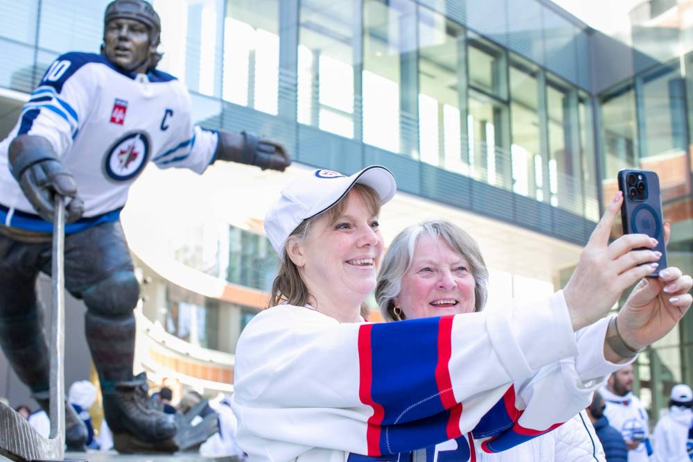 BROOK JONES / FREE PRESS
                                Jets fans Kelly Penner Hutton (left) takes a selfie with her mom Louise Hutton as they stand in front of the Dale Hawerchuk statue before the start of Game 1 of the National Hockey League Stanley Cup playoff between the hometown Winnipeg Jets and the visiting St. Louis Blues in Winnipeg on Saturday. The Dale Hawerchuk statue dons a Winnipeg Jets jersey.