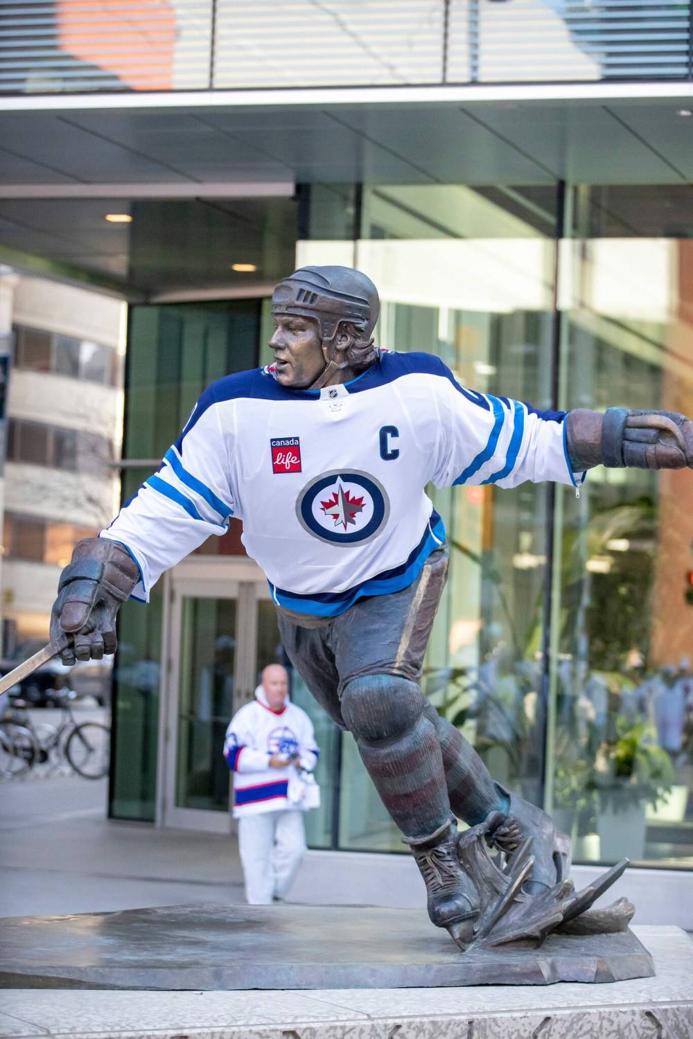 BROOK JONES/FREE PRESS A Jets fan walks behind the Dale Hawerchuk statue before the start of Game 1 of the National Hockey League Stanley Cup playoff between the hometown Winnipeg Jets and the visiting St. Louis Blues in Winnipeg on Saturday. The Dale Hawerchuk statue dons a Winnipeg Jets jersey.