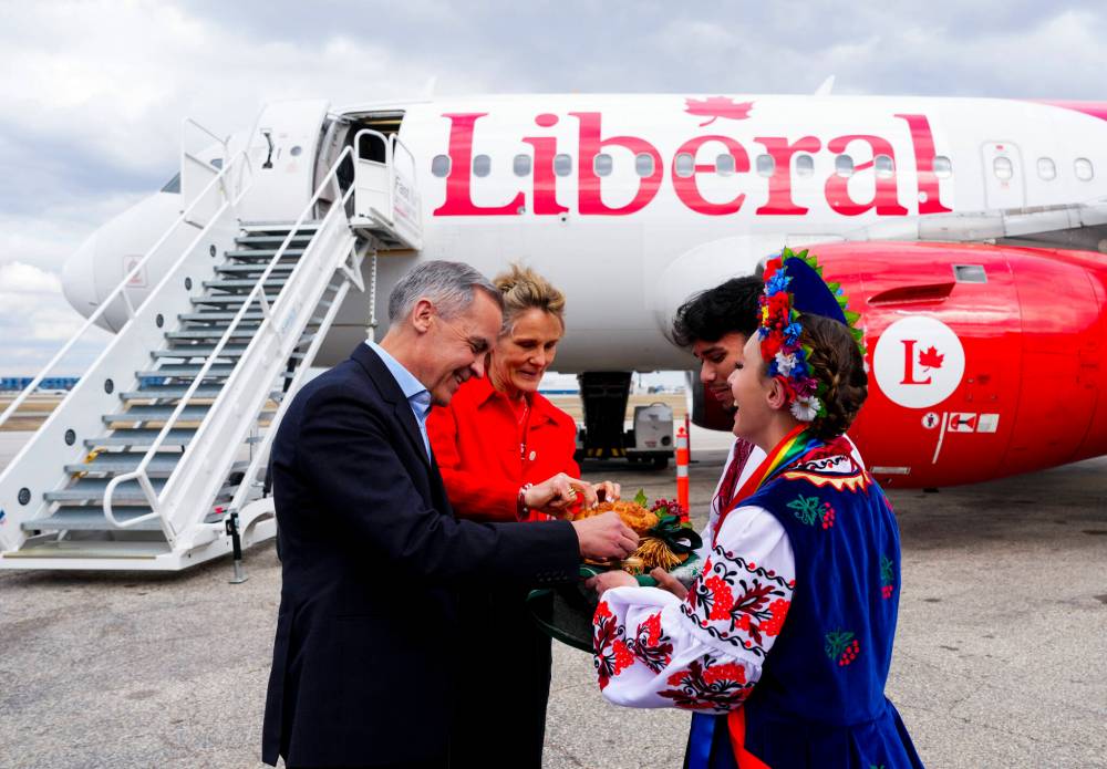 Sean Kilpatrick / THE CANADIAN PRESS
Liberal Leader Mark Carney and wife Dianna Fox Carney are presented with Ukrainian bread and salt by members of the Ukrainian community Julianna Chubenko and Anton Verma as they arrive in Winnipeg, Thursday.