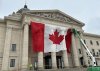 Workers install a large Canadian flag on the front of the Manitoba legislative building in Winnipeg on Tuesday Mar. 4, 2025. THE CANADIAN PRESS/Steve Lambert