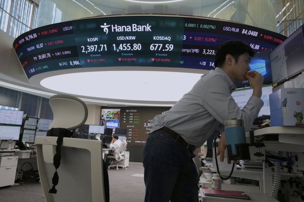 A currency trader watches monitors near a screen showing the Korea Composite Stock Price Index (KOSPI), top center left, and the foreign exchange rate between U.S. dollar and South Korean won, top center, at the foreign exchange dealing room of the KEB Hana Bank headquarters in Seoul, South Korea, Friday, April 11, 2025. (AP Photo/Ahn Young-joon)