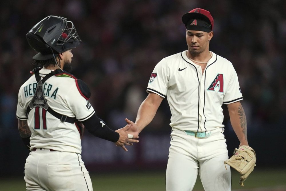 Arizona Diamondbacks pitcher Justin Martinez, right, celebrates a win against the Atlanta Braves as he shakes hands with Diamondbacks catcher Jose Herrera after the final out in the ninth inning of a baseball game Sunday, April 27, 2025, in Phoenix. (AP Photo/Ross D. Franklin)