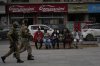 Indian tourists rests on a bench as policemen guard near a clock tower at city centre in Srinagar, Indian controlled Kashmir,Tuesday, April. 22, 2025. (AP Photo/Mukhtar Khan)