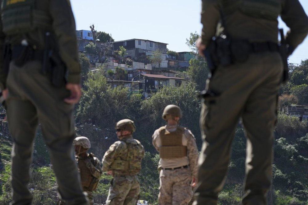 FILE - Border Patrol agents and members of the military look towards Tijuana, Mexico, as they stand between two border walls, March 21, 2025, in San Diego. (AP Photo/Gregory Bull, File)
